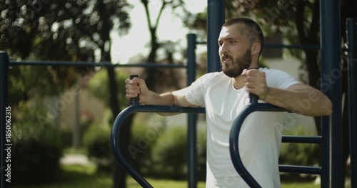 Young man performs abs exercise outdoors, street workout, slow motion, middle close up 