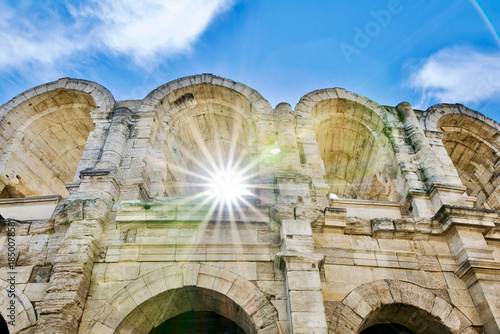 Arches of the Roman arena of Arles crossed by beautiful rays of sun in France.