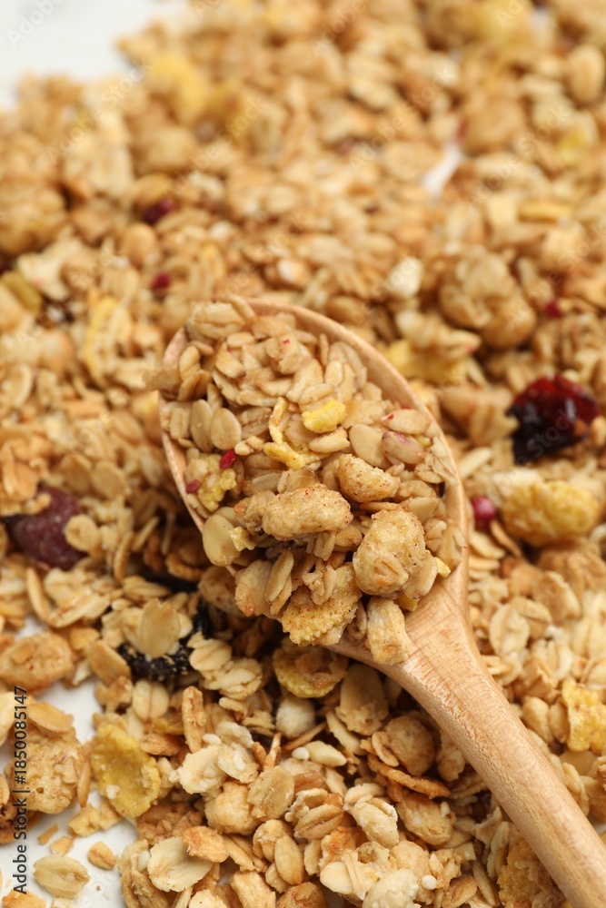 Obraz premium Tasty granola and spoon on white table, closeup
