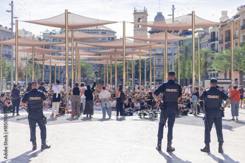 Εκτύπωση καμβά A back view of a Spanish National Police officers standing guard at a sunlit public event in Valencia