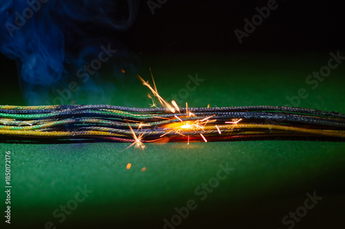 Smoldering electrical wires emit smoke and sparks when the system is dangerously overloaded.