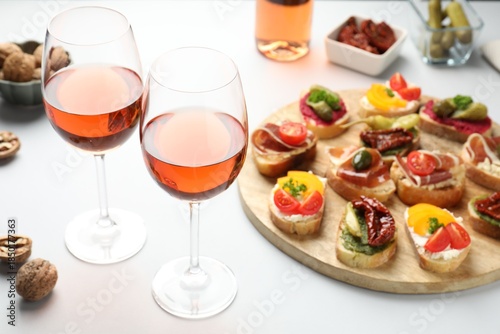 Billede på lærred Tasty bruschettas with prosciutto and rose wine served on white table, closeup