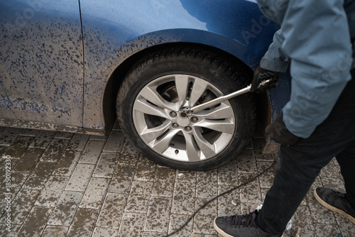 Foto A man tightens wheel nuts with a torque wrench
