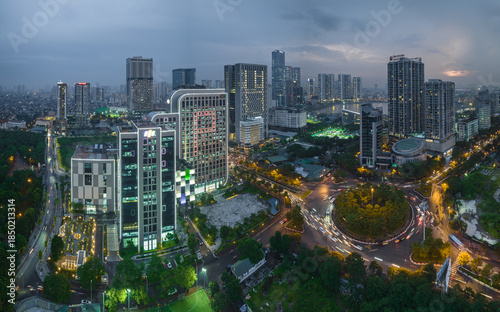 Aerial view of city buildings and roundabout with streaking lights under a dusky sky, Hanoi, Vietnam.