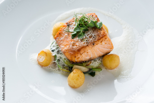 Salmon fillet dish with potatoes, vegetables, and foam sauce