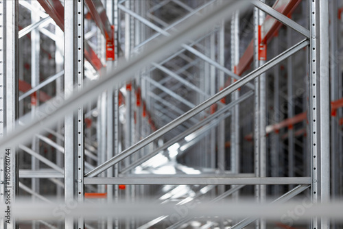 Close-up view of industrial metal shelving racks in a warehouse or factory. The steel structure with orange beams and metal efficient storage system. Logistics industrial design concepts