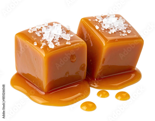Two glistening caramel cubes topped with coarse salt, sitting on a glossy caramel puddle