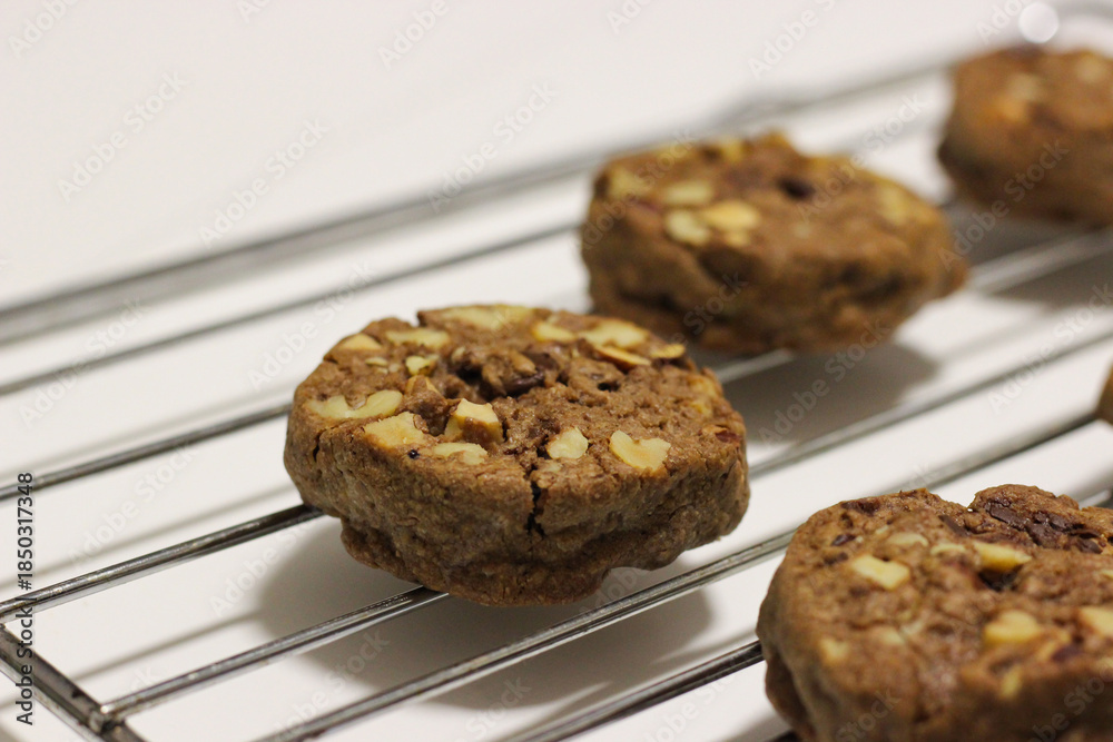Fototapeta premium Close up of a homemade chocolate chip cookie with nuts on a cooling rack
