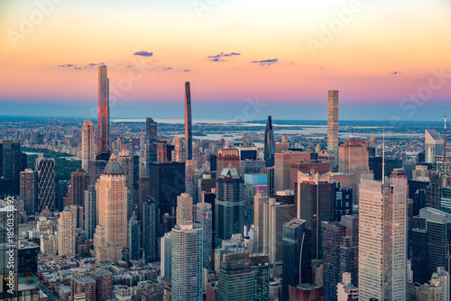 The iconic Billionaires Row skyscrapers rise above the dense Midtown Manhattan skyline during a vibrant sunset.