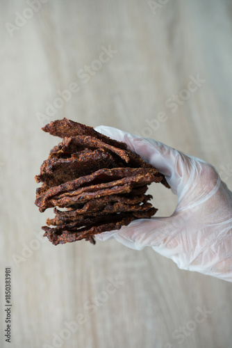 Pieces of dried meat in hand vertical close-up