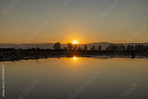 Sunset over water with distant trees