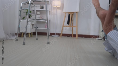 An elderly man holding a walking aid falls while learning to walk. He is assisted by a young female caregiver. Concept of elderly care and rehabilitation