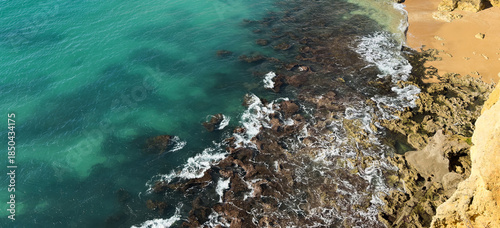 Ocean waves rolling to the rocky shore. Beautiful seascape. Aerial top view of the beautiful ocean rocky shore with rolling waves. Drone is hovering over rolling ocean waves to rocky shore