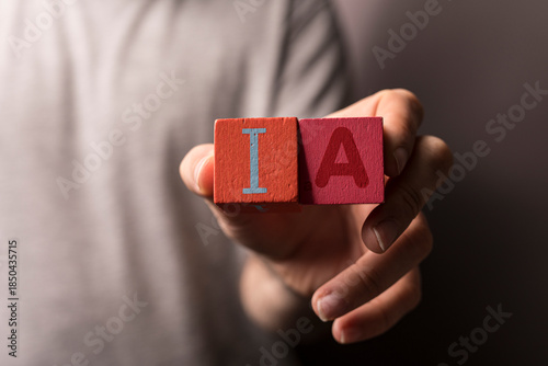 Photos Close-up of a person's hand holding wooden blocks with the letters IA representi