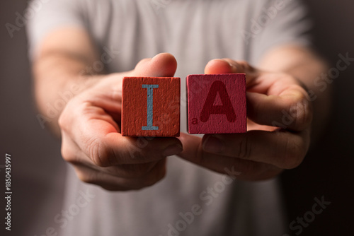 Fotografie Image of a person holding wooden blocks spelling 'IA,' highlighting artificial i