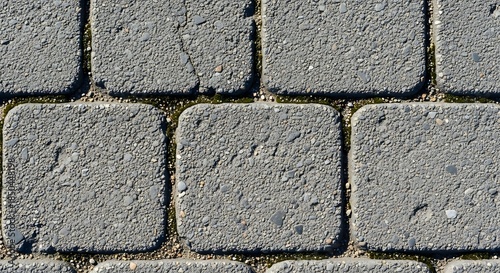 Close-up Texture of Gray Paving Stones with Green Grass Between Them.