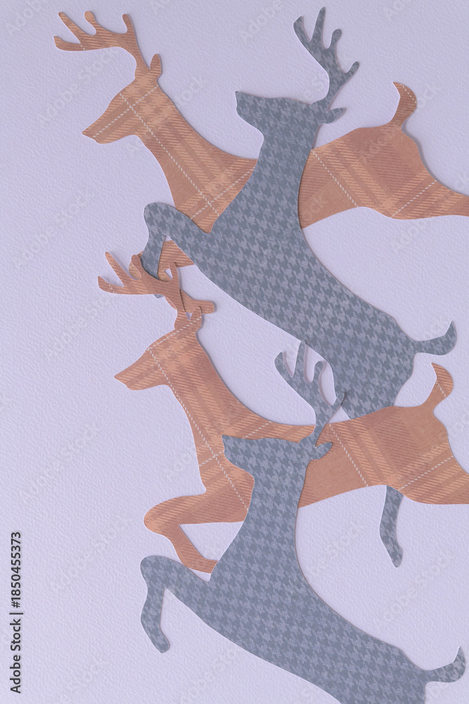 Fototapeta premium leaping reindeer shapes machine-cut from gray and brown paper with plaid pattern
