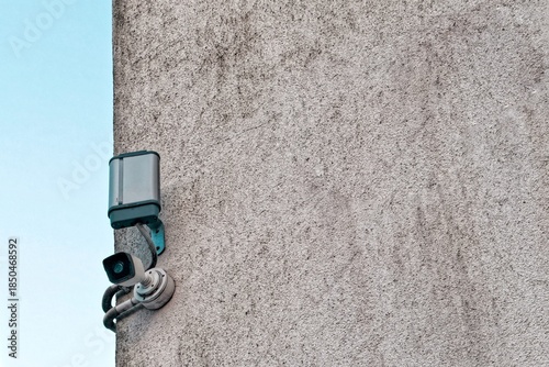 Surveillance camera mounted on a concrete wall against a clear sky, symbolizing security, monitoring, privacy, and urban technology.