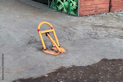 Orange parking barrier folded down on rough pavement, an urban still life showing wear, function, and utilitarian design.