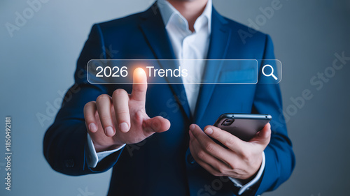 Businessman in blue suit searching 2026 trends on smartphone
