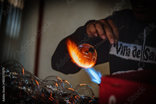 Glass blowing Christmas ornament over open flame
