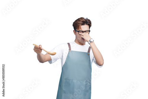 Unpleasant Culinary Experience: A chef in an apron recoils from a dish, using hand to cover nose and holding a wooden spoon