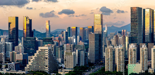 Dense modern city skyline with towering skyscrapers reflecting golden light at sunset in Shenzhen, China.