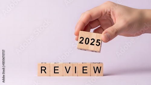 Hand holding wooden block with 2025 above review blocks