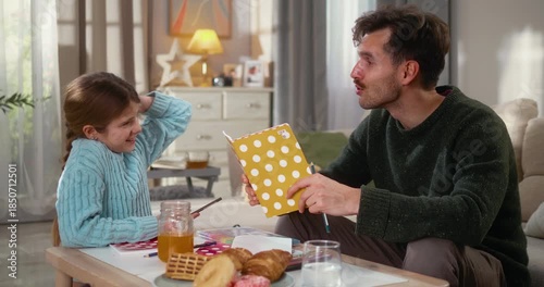 Father and daughter happily work on homework together in the living room. Warm family connection, learning, support, and everyday home life.