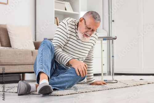 Billede på lærred Senior man sitting on floor after fall with walker at home