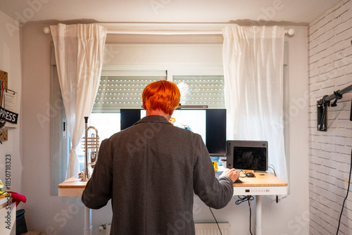 Red-haired man working at standing desk in home office