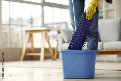 Young woman with mop and bu...