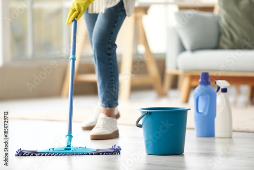 Konstfotografi Young woman with plastic bucket mopping floor at home