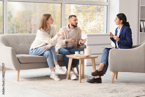 Female family mediator talking with young couple in office