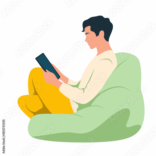 A relaxed young man sits comfortably on a bean bag chair, engrossed in a tablet, embodying the essence of modern leisure activities and the joy of digital exploration.