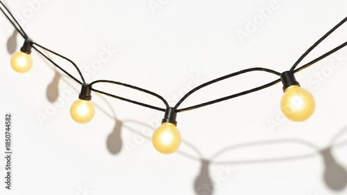 A string of four warm glowing yellow light bulbs hanging against a white background, casting distinct shadows.