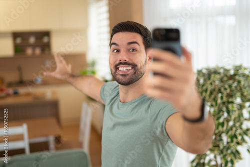 Obraz na płótnie Young happy man vlogging and showing home on smartphone