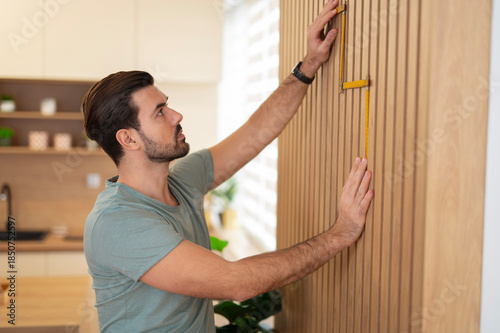 Fotografia Man measuring wood paneling for home improvement project