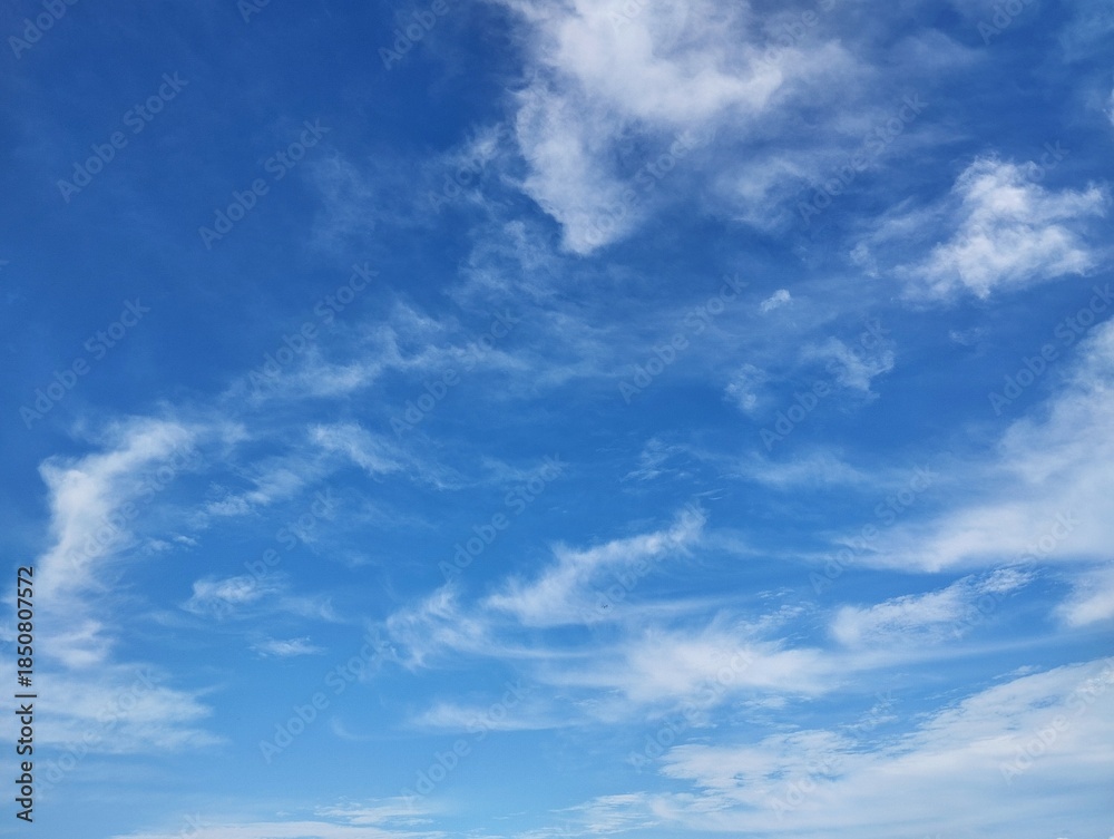 Fototapeta premium Clear blue sky with a few clouds. The sky is very bright and the clouds are scattered throughout in summer season