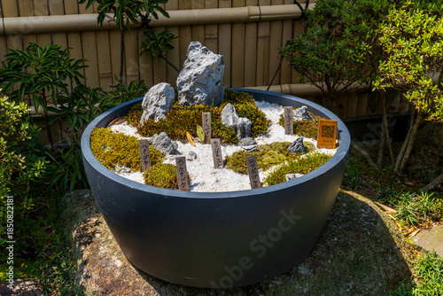 Sticker Miniature japanese zen rock garden in round pot with moss stones and white grave