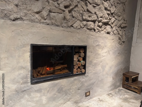 Modern Concrete Fireplace: Minimalist earthy fireplace set within a concrete enclosure, featuring a black wall cutout niche for storing firewood next to the fire.