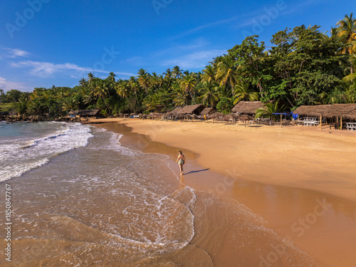 Young Woman Walking on Golden Sand Beach with Thatched Beach Huts, Goyambokka Beach, Sri Lanka