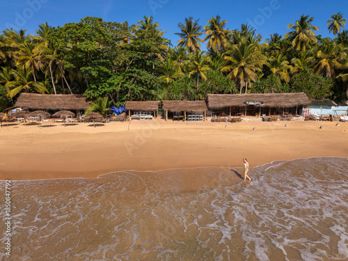 Young Woman Walking on Golden Sand Beach with Thatched Beach Huts, Goyambokka Beach, Sri Lanka