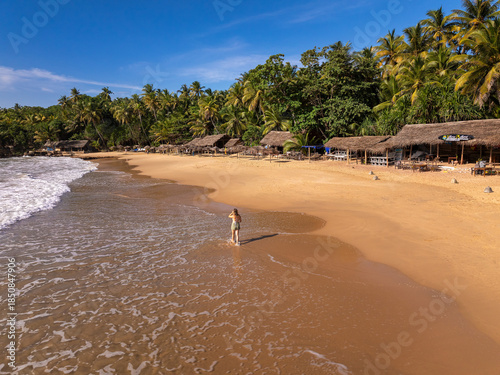 Young Woman Walking on Golden Sand Beach with Thatched Beach Huts, Goyambokka Beach, Sri Lanka