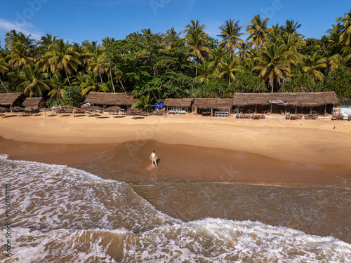 Young Woman Walking on Golden Sand Beach with Thatched Beach Huts, Goyambokka Beach, Sri Lanka