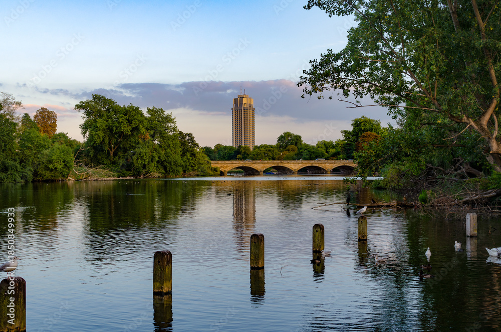 custom made wallpaper toronto digitalView of a city building over a calm river with trees and a bridge in the background during early evening hours .