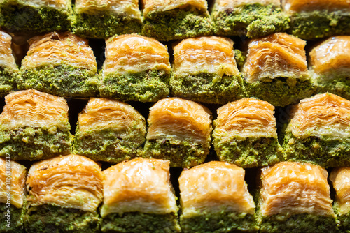 Extreme close-up of Turkish baklava with pistachios, showing flaky pastry layers and chopped nuts. Traditional dessert detail.

