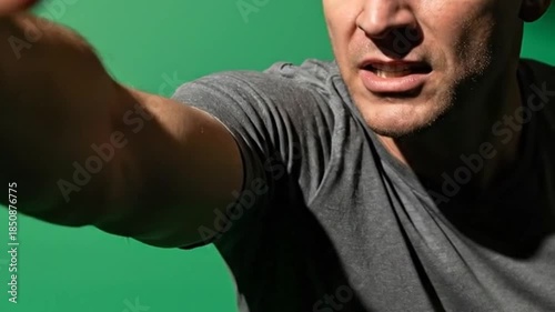 Furious man screaming and threatening, close-up of face with angry expression, shot against green