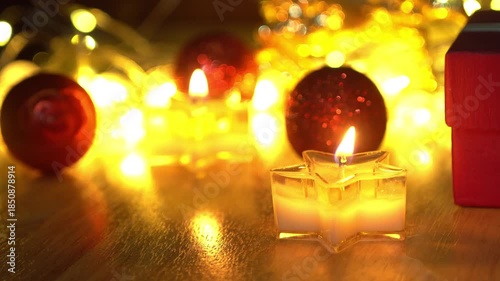 Red Christmas ball and candlelight on a wooden table.