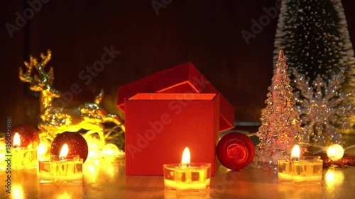 Red gift box and candlelight on a wooden table.